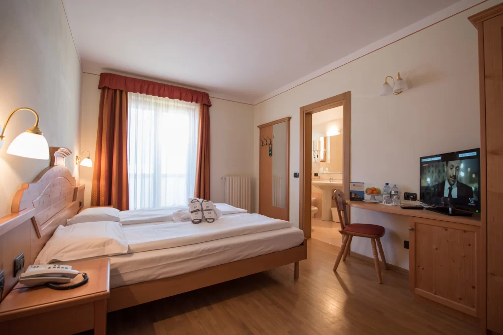 Camera d'hotel accogliente con letto matrimoniale, tv, e bagno privato.