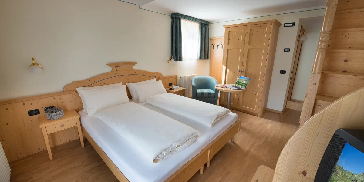 Camera d'albergo accogliente con arredamento in legno e letto matrimoniale.