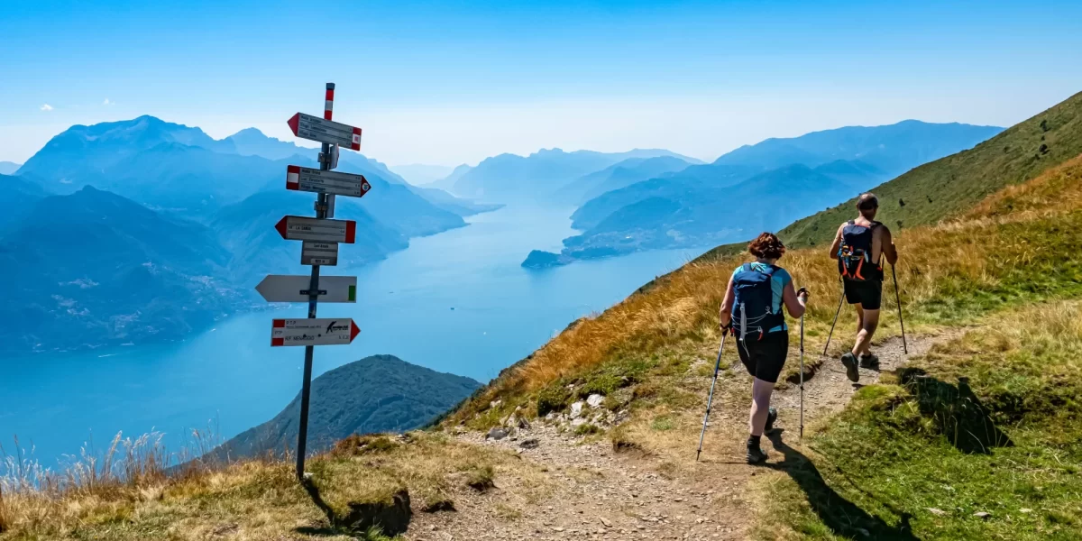 Escursionisti sul sentiero di montagna con vista panoramica su un lago e montagne.