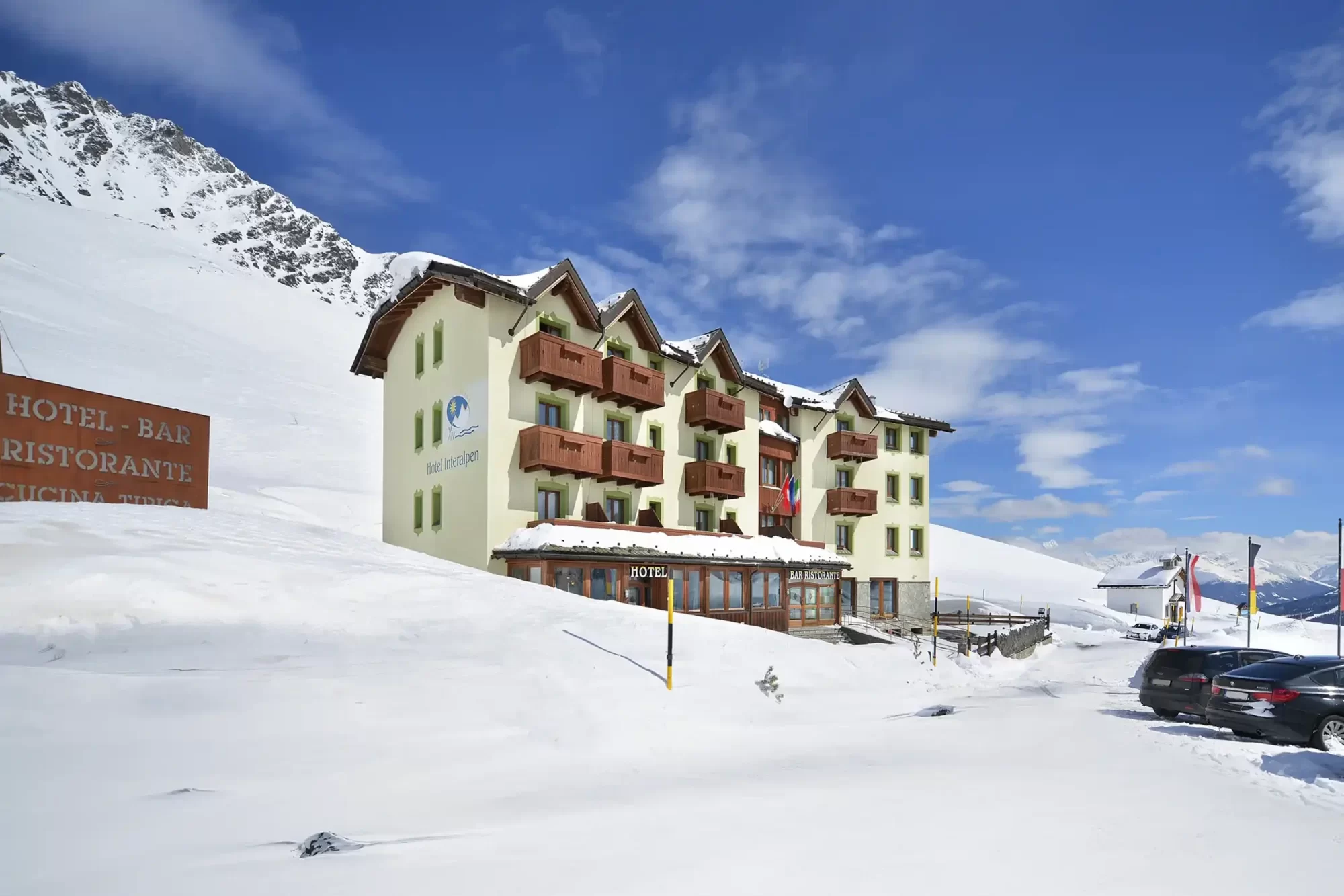 Hotel alpino innevato in montagna sotto un cielo azzurro.