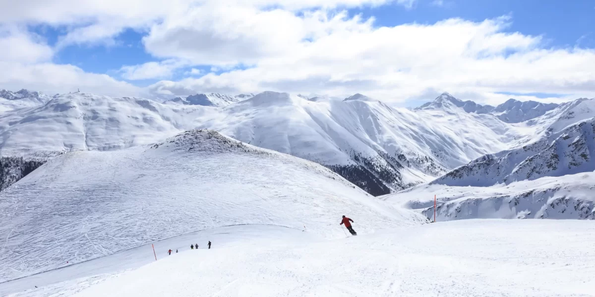 Scenico panorama di montagne innevate con sciatori in discesa.
